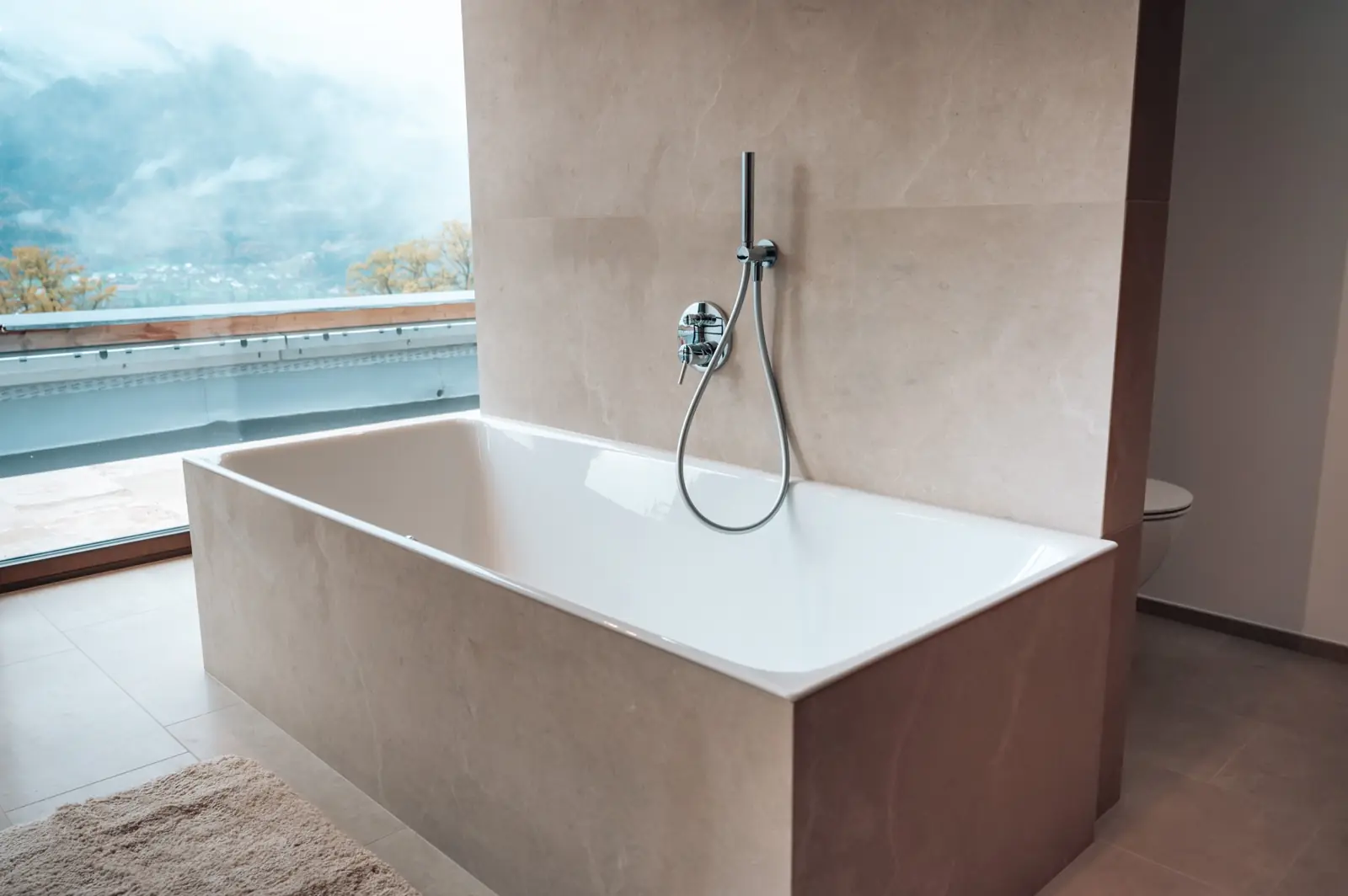 Freistehende Badewanne vor einem Fenster mit Bergblick