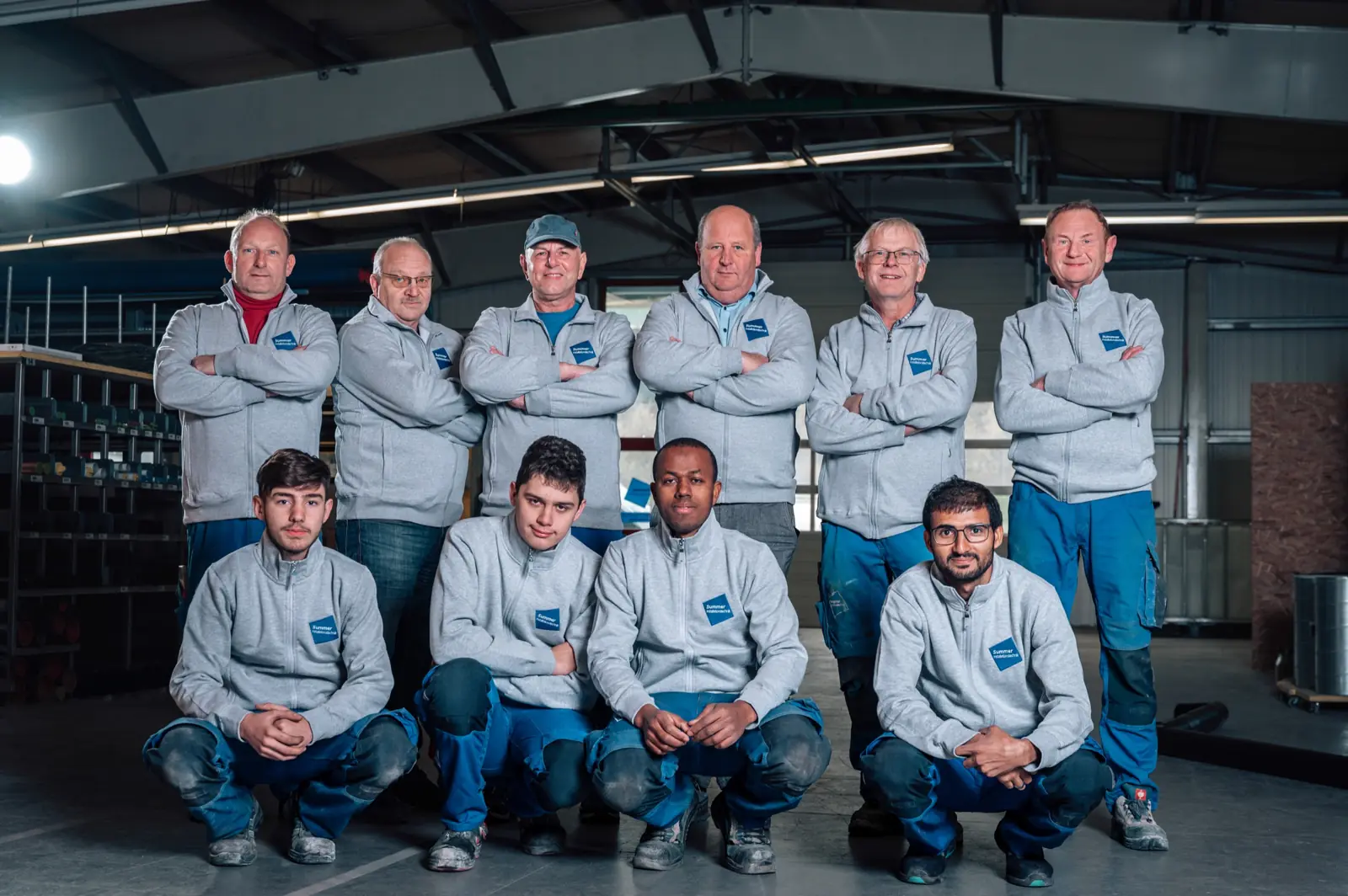 Das Summer-Team in grauen Firmenjacken in der Werkhalle in Frastanz